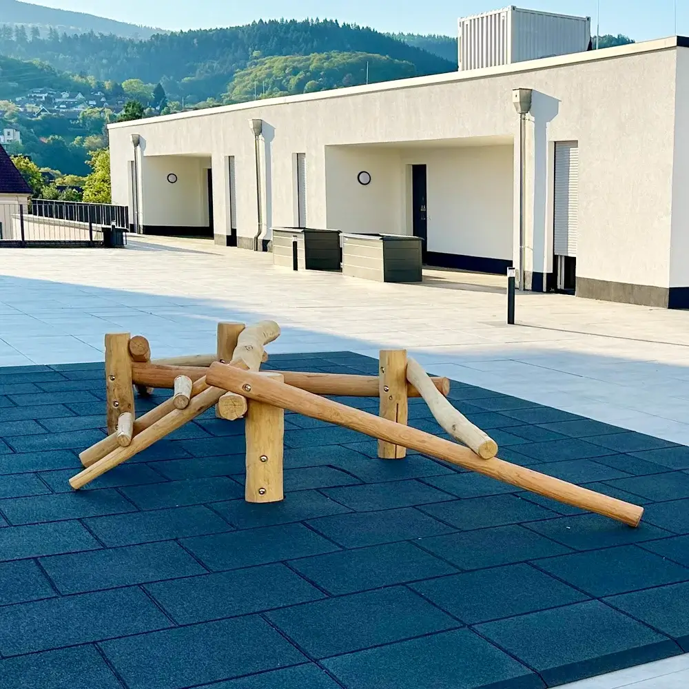 kleines und niedriges Balanciergerüst Rautenform aus natürlich gewachsenen Robinienstämmen. Das Gerät steht auf einer Fallschutzfläche aus schwarzen Gummiplatten.