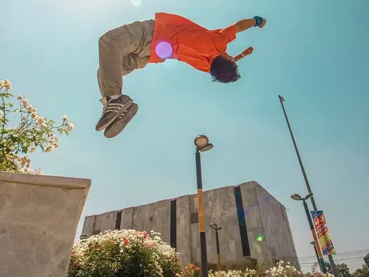 Symbolbild für Fallhöhe beim Parkour: Junger Mann macht einen Backflipp von einer Betonkante. 