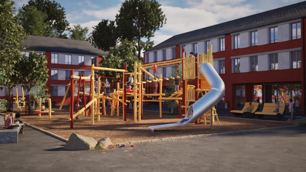 Asphaltierter Pausenhof einer Grundschule U-förmig von roten Schulgebäuden mit großen Fensterfronten umgeben. In der Mitte des Schulhofs eine große rechteckige Fläche gefüllt mit Holzschnitzeln. Auf der Fläche zwischen jungen Bäumen ein großes Klettergerüst aus Robinienholz mit einem zentralen sechseckigen Turm. Auf 3m Höhe startet an dem Turm eine Röhrenrutsche aus Edelstahl. Im Hintergrund noch zu erkennen: eine Tampenschaukel und eine Hängematte.