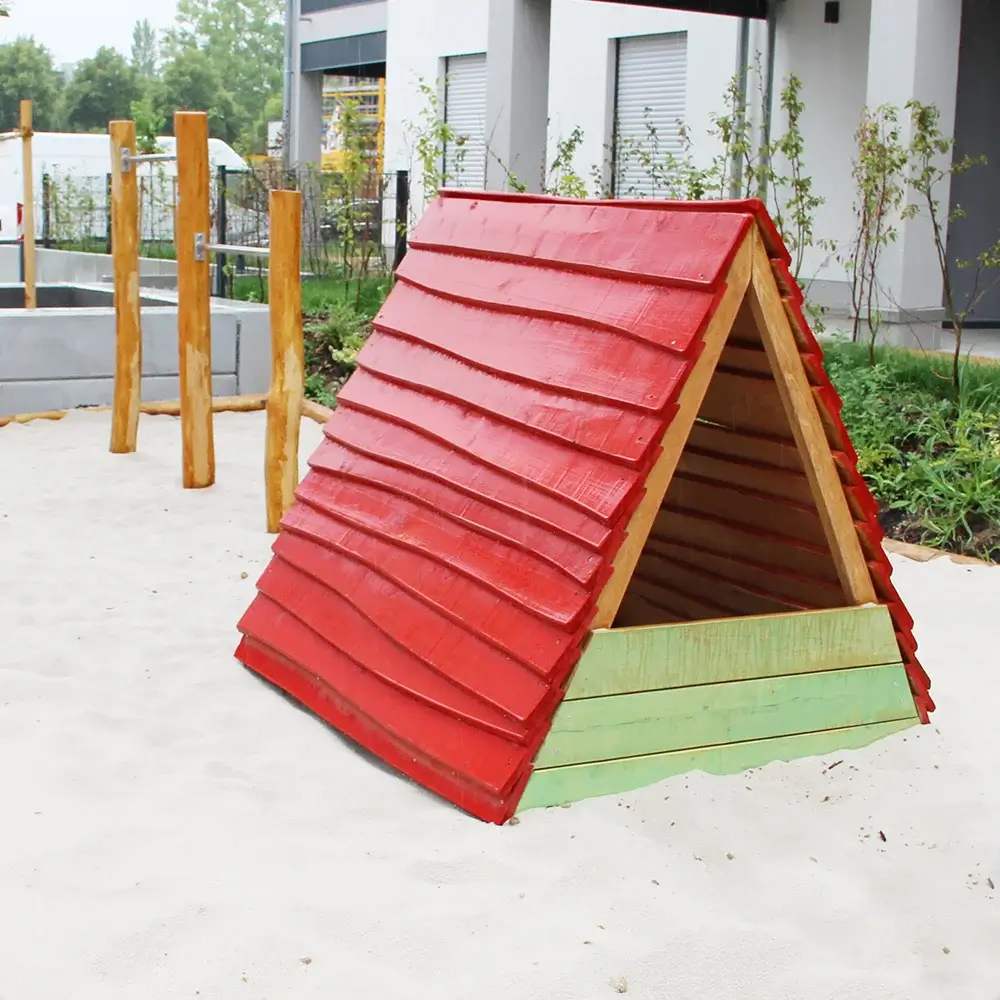 Kleines Spielhaus in Zeltform mit rotem Holzdach und grünem Sockel - auf Spielplatz mit Fallschutzsand.