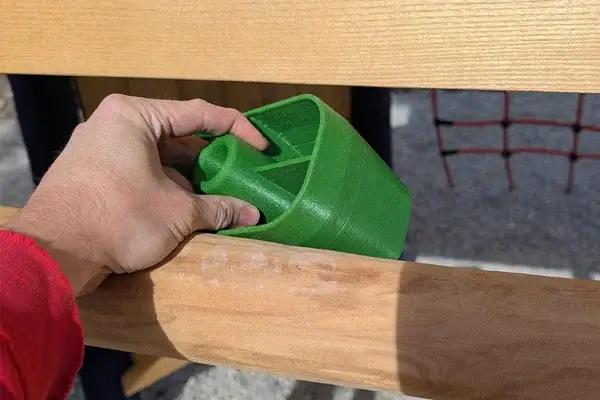 Detailaufnahme: Spielplatzprüfung mit dem Prüfkörper C zwischen der letzten Leitersprosse und einer Turmplattform. Prüfung nicht bestanden: Fangstelle für Kopf