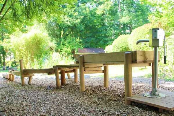 Individueller Wasserlauf Ansicht Pumpe: Im Vordergrund rechts eine Wasserpumpe von der aus das Wasser in ein Staubecken gepumpt werden kann. Im anschluss, etwas abgestuft weitere Matschkästen und hölzerne Rinnen, die sich im Hintergrund verlieren